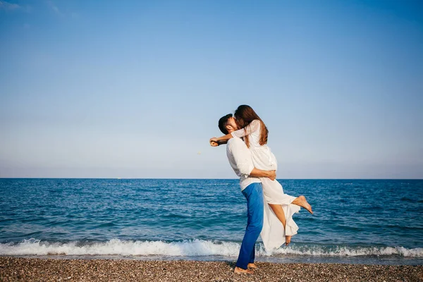 Felice giovane coppia sulla spiaggia in amore abbracciare e abbracciare sorridente — Foto Stock