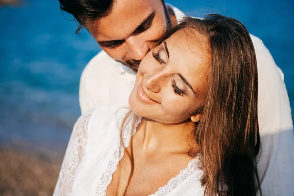 Gelukkig jong koppel op het strand in liefde omarmen en knuffelen glimlachen — Stockfoto