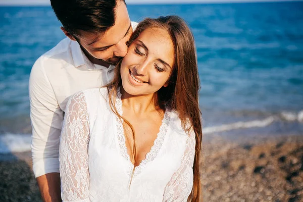 Gelukkig jong koppel op het strand in liefde omarmen en knuffelen glimlachen — Stockfoto