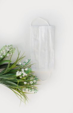 Çiçekli sade bir arka planda tıbbi maske