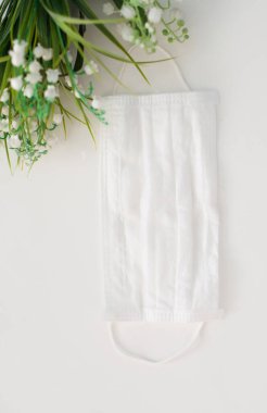 Çiçekli sade bir arka planda tıbbi maske
