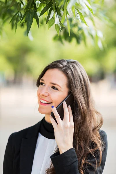 Mujer alegre hablando de teléfono bajo el árbol — Foto de Stock