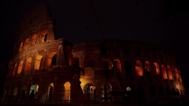 Colosseum met steiger in restauratie 's nachts Rome, Italië. Romeins amfitheater met lichte verlichting aan de donkere nachtelijke hemel. Renovatie, reparatie, retoucheren concept. Bezienswaardigheden en architectuur — Stockvideo