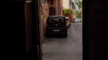 Çekici kız, eski bir şehir caddesinde kapı aralığındaki bir kameranın önünden geçiyor. Trastevere, Roma, İtalya