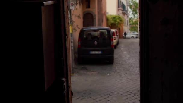 Menina atraente caminha ao longo de uma rua da cidade velha passado uma câmera localizada em uma entrada. Trastevere, Roma, Itália — Vídeo de Stock