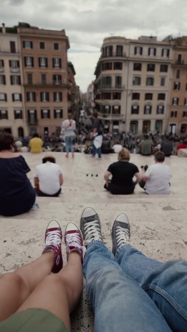 Roma, İtalya - 14 Mayıs 2019: Renkli spor ayakkabılı iki turist İspanyol Merdivenlerinin basamaklarında oturuyorlar. Roma, İtalya. Yukarıdan çekilmiş Selfie dikey videosu — Stok video