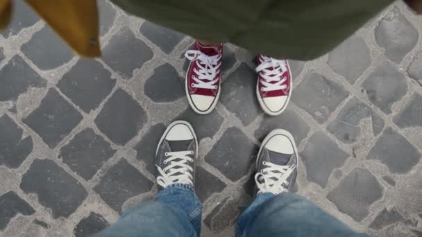 Baskets rouges et bleus dansant sur des pavés. Vidéo selfie prise d'en haut. Les jambes masculines et féminines sont en baskets colorées — Video