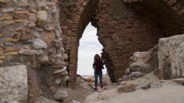 Güzel genç bir kadın, İtalya 'nın Ladispoli kentindeki eski bir Torre Flavia kalesinin kalıntılarında tuğla kemerden geçiyor. Ön görünüm