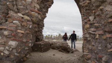 Aşıklar el ele tutuşuyorlar. Ladispoli, Roma, İtalya 'daki eski Torre Flavia' nın yıkılmış kemerine.