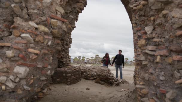 Liefhebbers die hand in hand gaan in de verwoeste boog van het oude Torre Flavia in Ladispoli, Rome, Italië — Stockvideo