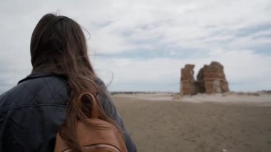Sırt çantalı bir turist kız Ladispoli, İtalya 'daki eski bir kalenin kalıntılarına yaklaşıyor. Arka görünüm