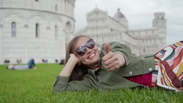 Jonge vrouw liggend op het gazon van Baptisterium van St. John op het Plein der Wonderen en tonen als — Stockvideo