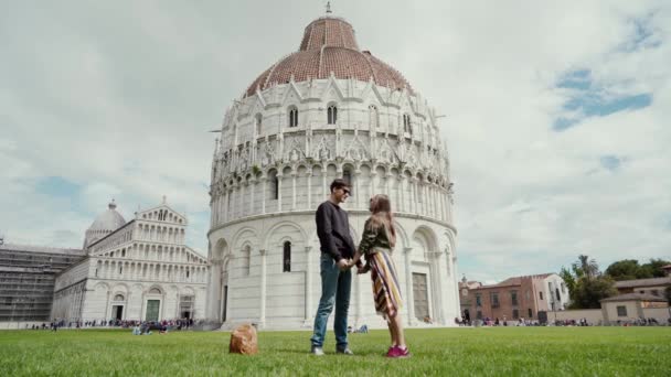Hermosa pareja está enamorada en vacaciones románticas. Baptisterio de San Juan está en el fondo, Pisa, Italia — Vídeo de stock