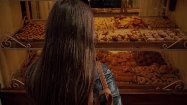 Woman shops desserts shop, looks at showcase, makes choice of Italian sweets — Stock Video