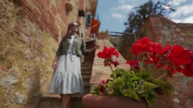 Girl in sunglasses goes down the stairs of old city walks past camera with smile