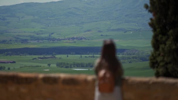 Blurred woman stands on observation deck in Pienza with green tuscan landscape — Stockvideo