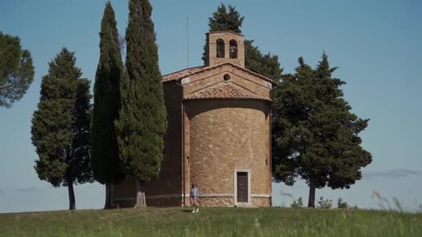Woman in dress  walks near old stone chapel Cappella di Vitaleta. Long shot — Stockvideo