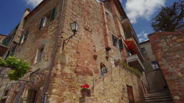 Pretty girl walks down stairs along stone wall of old building in ancient city — 图库视频影像