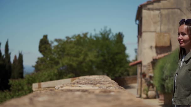 Beautiful girl walks up to stone parapet of medieval fortress and looks on vie — Stock Video