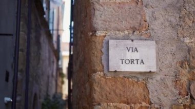Stone sign with Italian inscription Torta street on wall of italian building