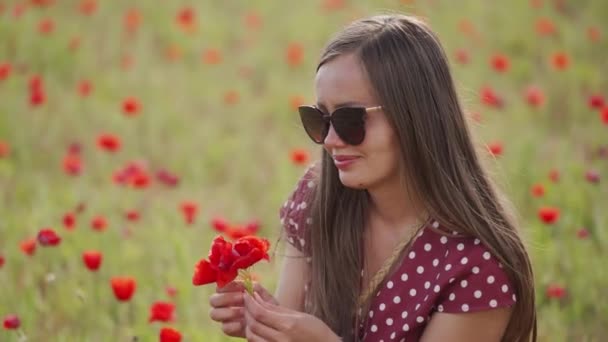Eine fröhliche Frau mit Sonnenbrille hält einen Strauß roter Mohnblumen in der Hand. Wildblumenstrauß — Stockvideo