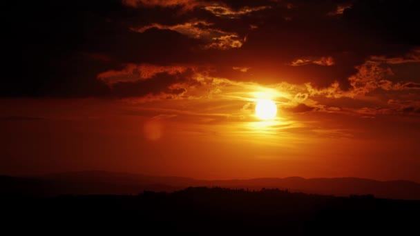 Beautiful red sunset in the evening cloudy sky over the Tuscan hills — Stockvideo