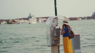 Şapkalı kadın, Grand Canal 'daki eski ankesörlü telefondan sarı etek çağrıları.