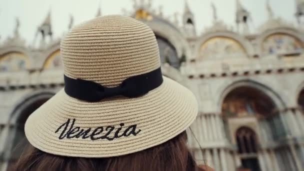 Ragazza in cappello di paglia si erge su Piazza San Marco, guarda alla Basilica di San Marco — Video Stock