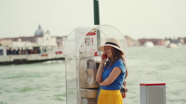 Lady in straw hat calls with old public phone located on Grand Canal embankment — Stock Video