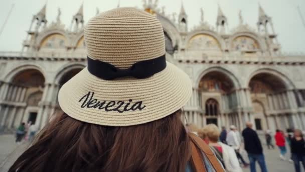 Brunette pike med hatt står på San Marco Square, ser til Basilica San Marco – stockvideo