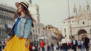 Şapkalı mutlu kız kollarını açmış San Marco Meydanı 'nda dönüyor.
