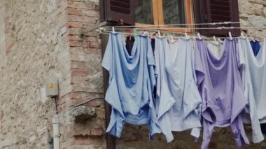 Yıkanmış gömlekler açık pencerenin altında iple kurudu. Çamaşırları kurutmanın geleneksel yolu.