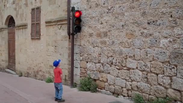 SAN GIMIGNANO, ITÁLIA - MAIO 17, 2019: Menino em boné à espera de semáforo verde — Vídeo de Stock