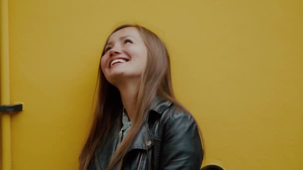 Retrato colorido de la joven mujer feliz mirando hacia arriba con sonrisa contra la pared amarilla — Vídeos de Stock