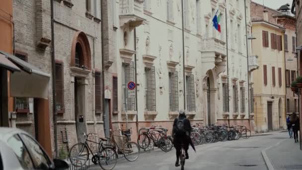 FERRARA, ITALIA - 20 DE MAYO DE 2019: Los lugareños van en bicicleta por la carretera sin coches del centro de la ciudad vieja — Vídeo de stock