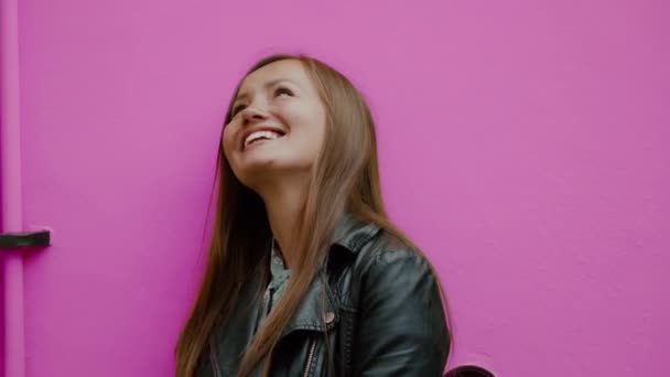 Retrato colorido de la joven mujer feliz mirando hacia arriba con sonrisa contra la pared rosa — Vídeos de Stock