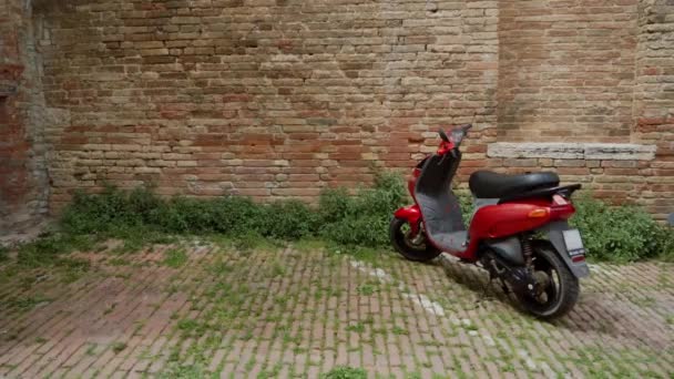 Urban scene with red motorbike parked background of an old brick wall — Stockvideo