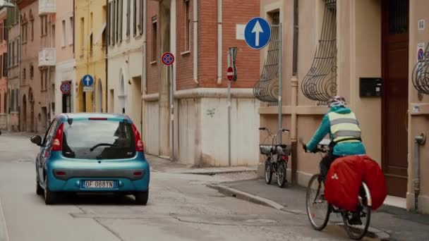 FERRARA, ITALY - 20 мая 2019 года: Голубая машина едет по улице, мужчина ездит на велосипеде, дорожный знак — стоковое видео