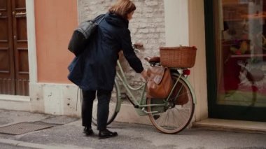 FERRARA, ITALY - MAY 20, 2019: Adult woman unlocks her bike, get started to ride