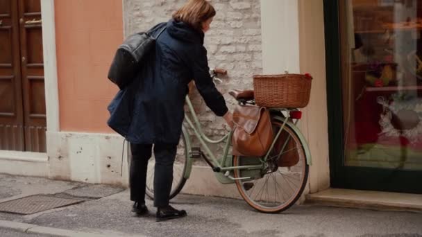 FERRARA, ITÁLIA - MAIO 20, 2019: Mulher adulta desbloqueia sua bicicleta, comece a andar — Vídeo de Stock