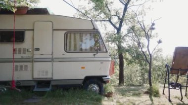 Genç bir kadın uyanıyor, karavanın kapısını açıyor ve güneş doğarken esniyor.