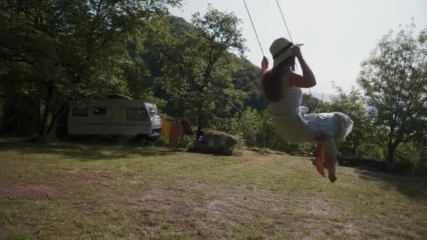 Jeune femme en robe romantique, chapeau balançant sur camping caravane. Vue latérale. Bien-être — Video