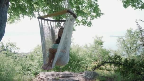 Barefoot meisje rusten in de schaduw in hangmat op de camping over het Gardameer, zonnige dag — Stockvideo