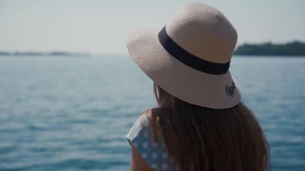 Chica en sombrero de paja se sienta descansando en la orilla del increíble color del lago en el día soleado — Vídeos de Stock