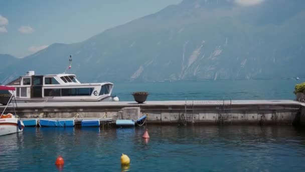 Pier de pedra com barco, vista panorâmica do lago, montanha à distância, céu azul dia ensolarado — Vídeo de Stock