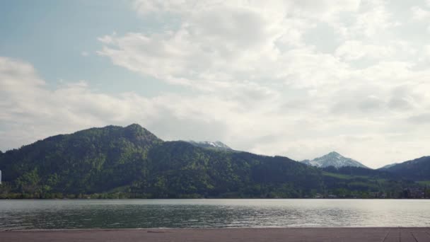 恋人たちはアルプスの景色を望むテゲルンゼー湖堤防に沿ってハンドルで歩く — ストック動画