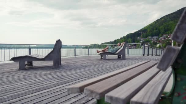 Woman in dress, sunglass relax lying on sun lounger by lake at empty relax zone — Stock Video