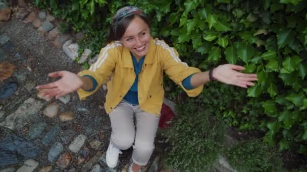 Chica feliz con una hermosa sonrisa se sienta y coge gotas de lluvia en las palmas de sus manos — Vídeos de Stock