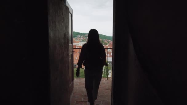 Ragazza va dal buio al balcone dell'antico castello con vista panoramica sulla città vecchia — Video Stock