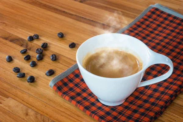Gorąca kawa espresso i ziarna kawy na drewnianym stole — Zdjęcie stockowe